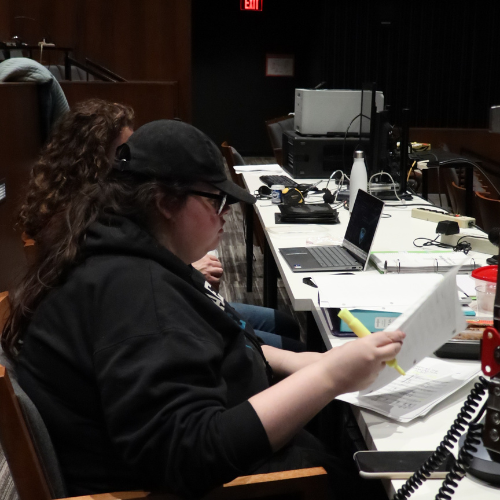 A stage management MFA student prepares sheet music during tech week
